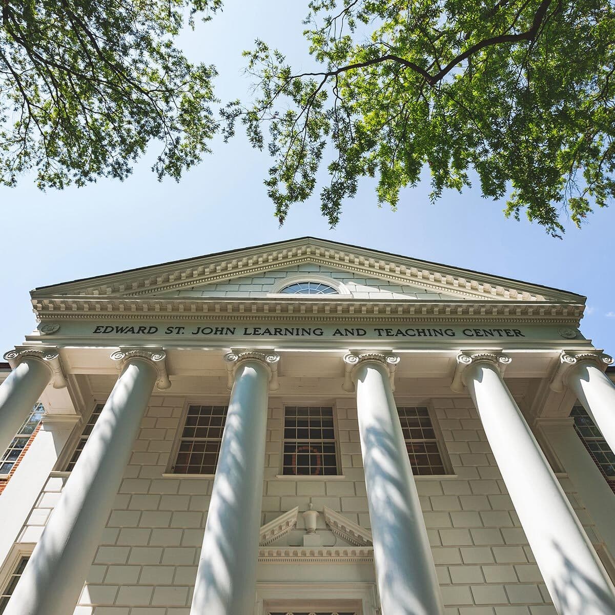 Looking up to the clean, light and grand entrance of the Edward St. John Learning and Teaching Center flanked by smooth neo classical pillars.