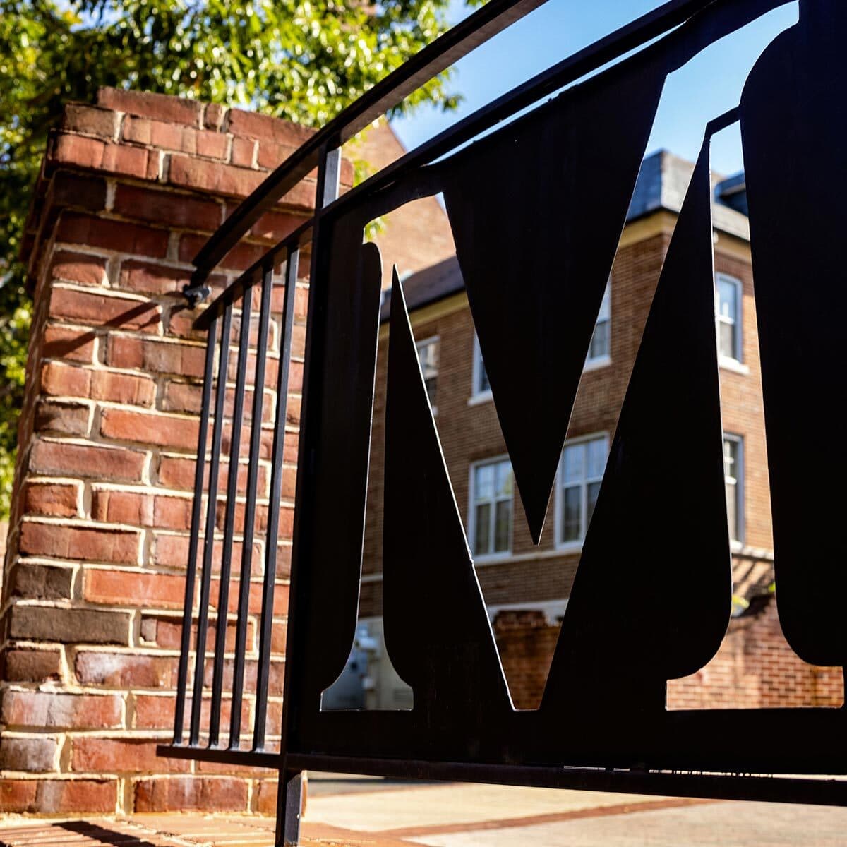 Silhouette of the Maryland M cut into a heavy dark coated metal plate set into an ornate fence